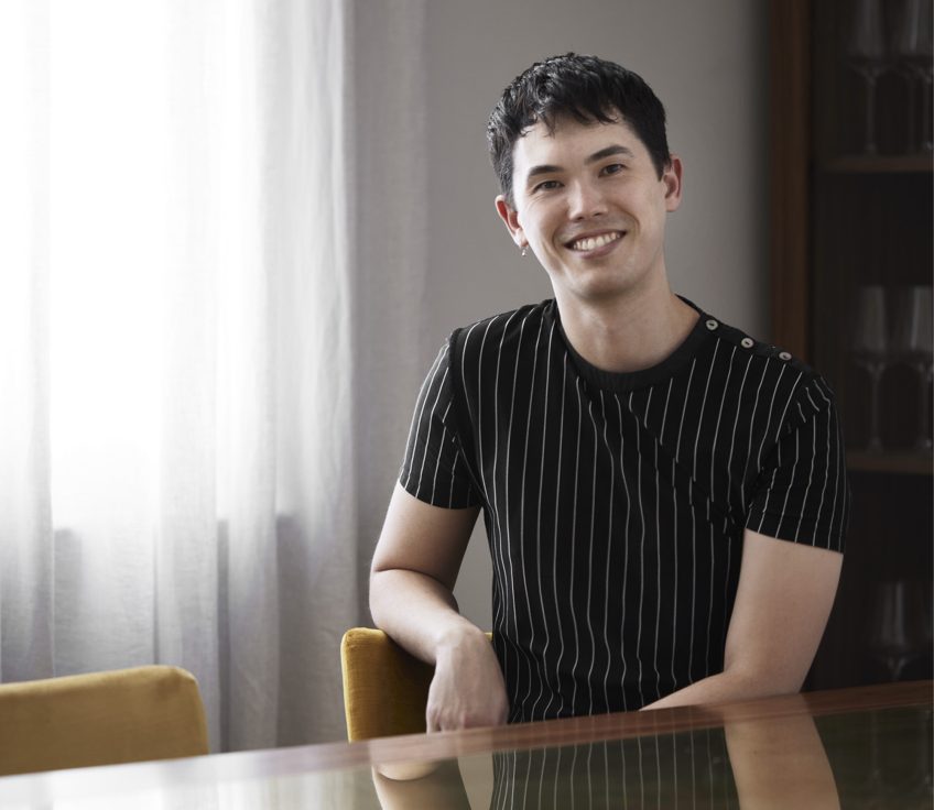 Ken Snell in a striped shirt sits at a reflective glass table.