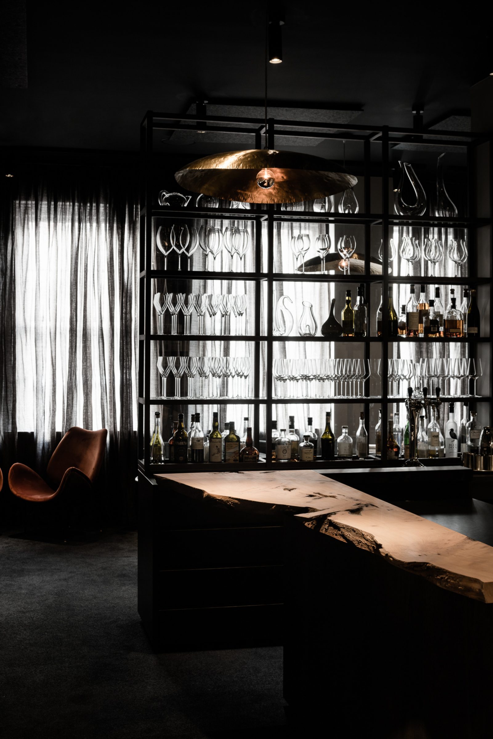 Modern bar interior with rustic wooden counter and glassware shelves from Attica.