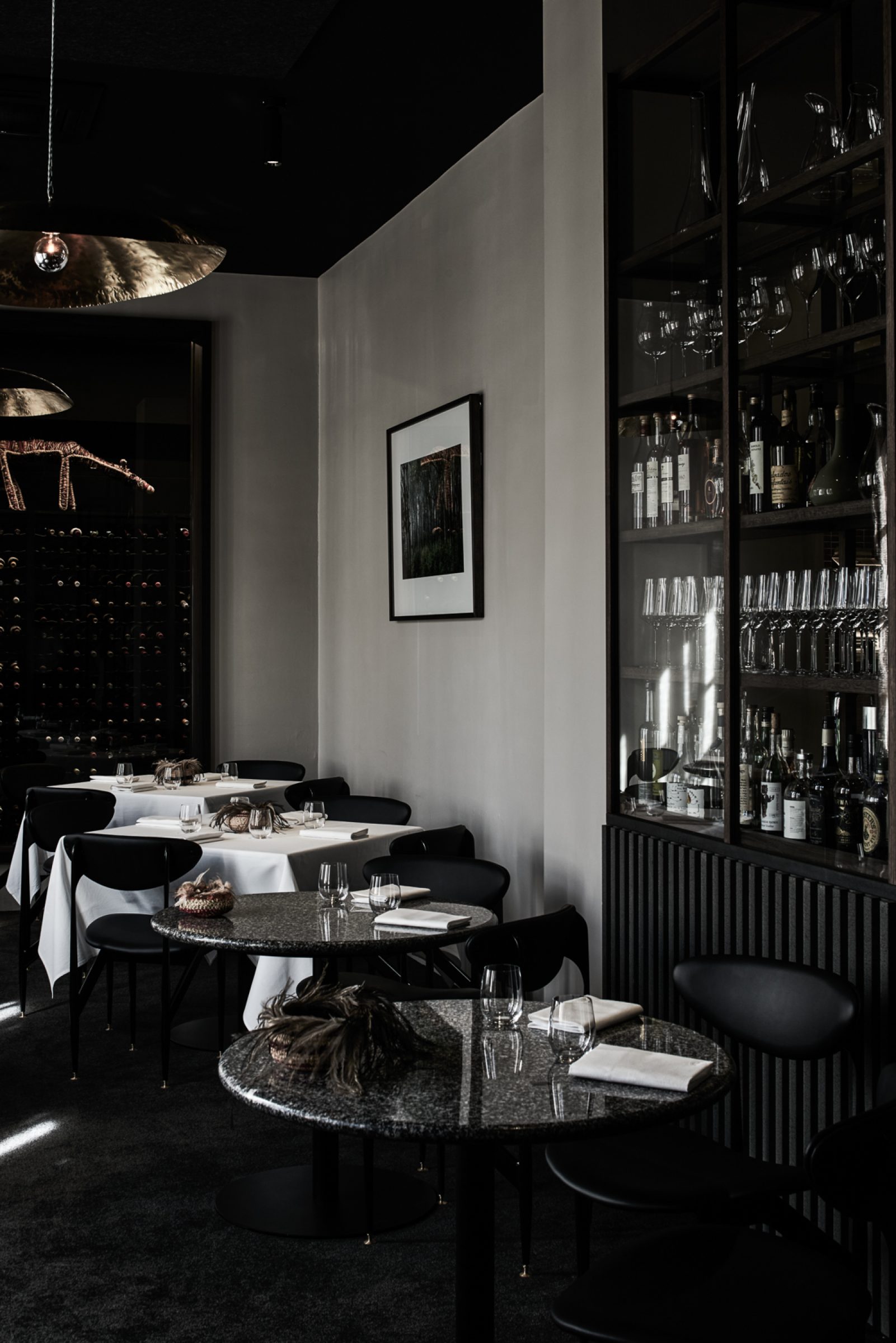 Elegant dining room interior from Attica featuring neatly set tables and a wine display cabinet.