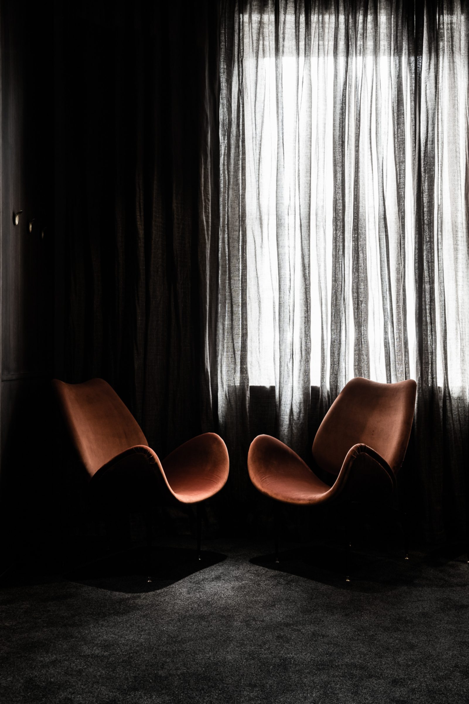 Two modern chairs in a dimly lit room from Attica.