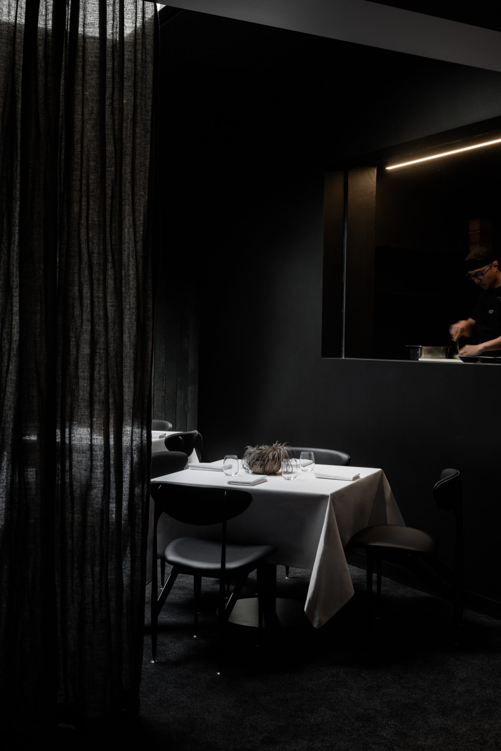 Dimly lit dining area with a set table in the Attica theme.