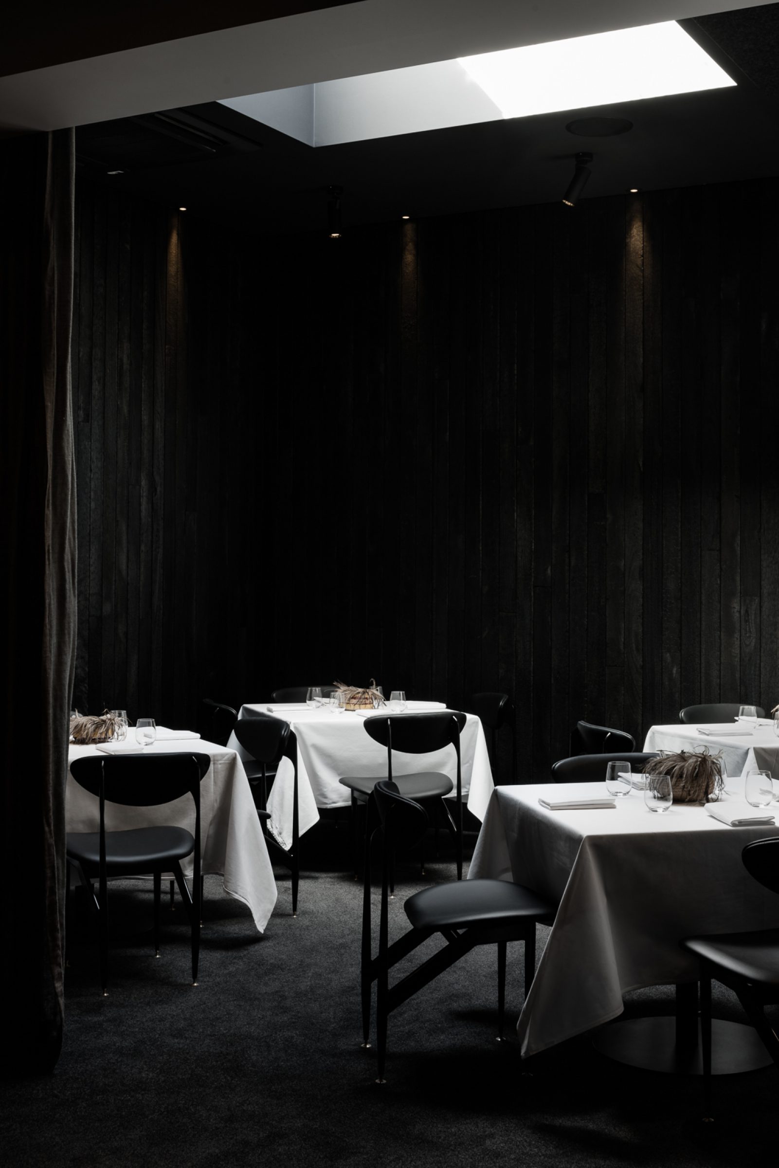 Elegant dining room with dark wood walls and white tablecloths from Attica.