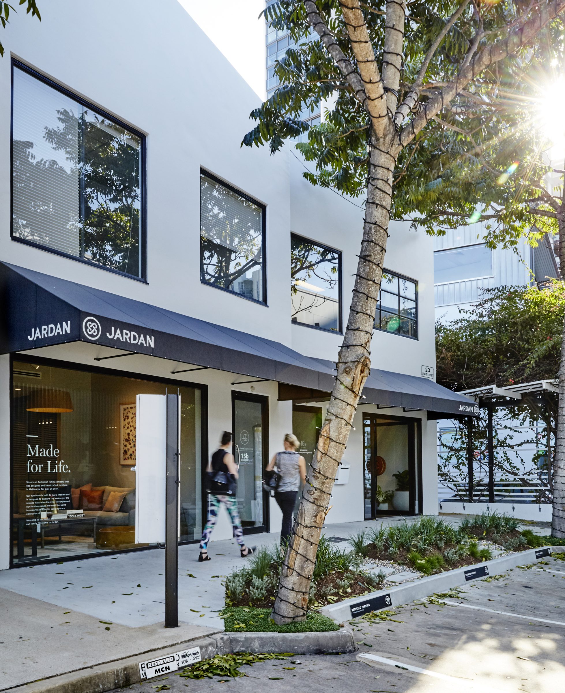 Exterior view of Jardan building in Brisbane with trees and people walking.
