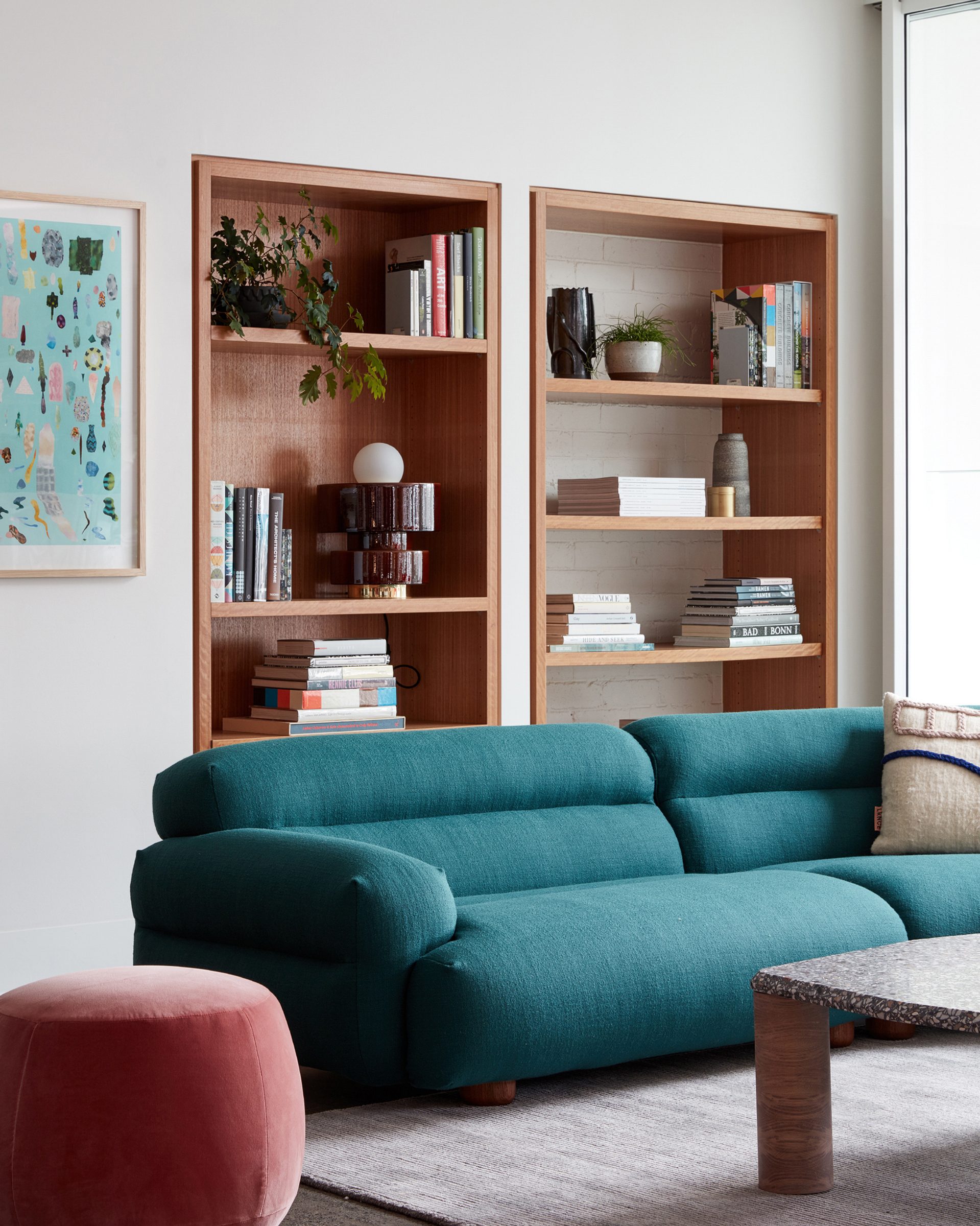 Modern living room with teal sofa and bookshelves in "Jardan, Melbourne" setting.