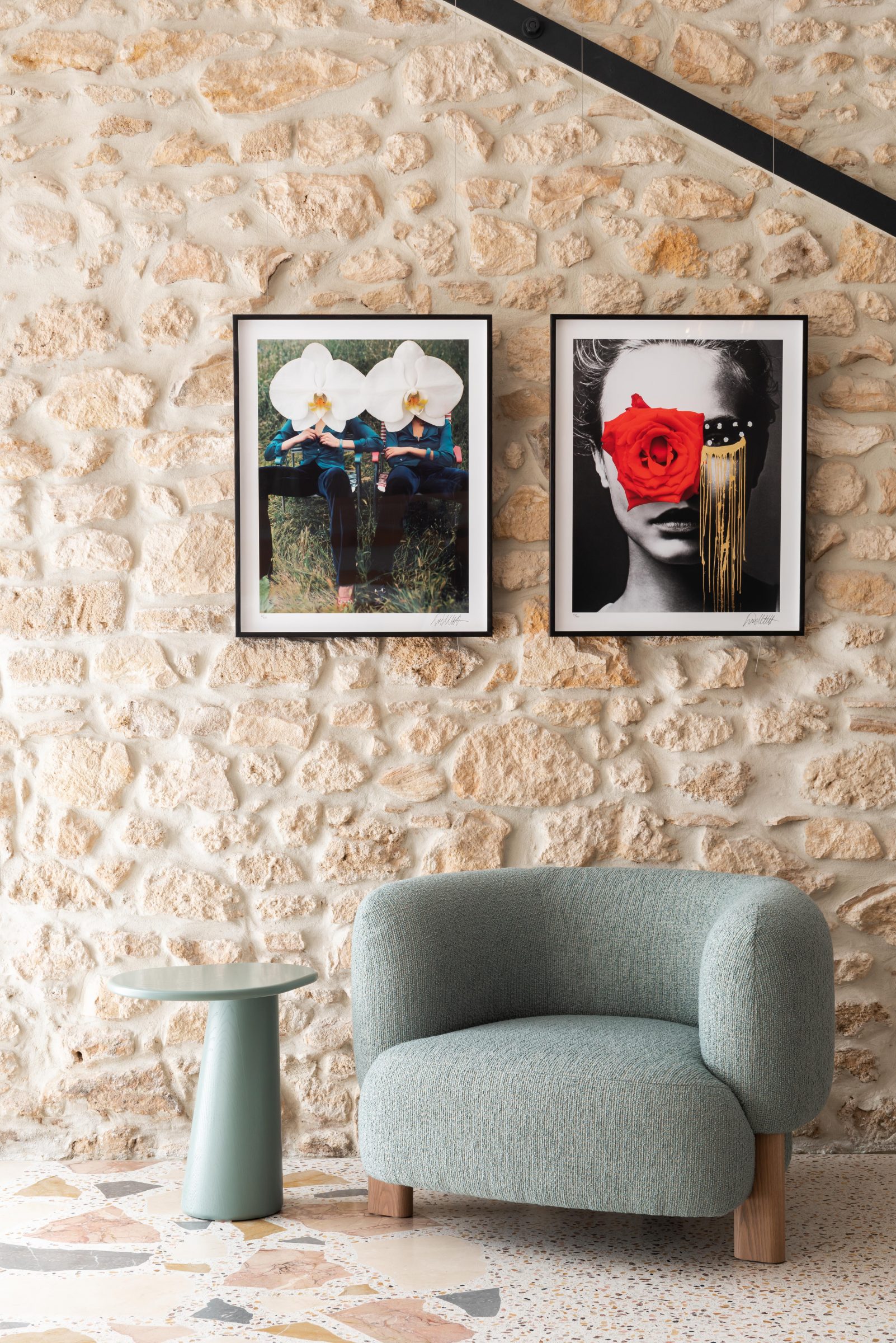 Jardan features two framed artworks on a stone wall above a modern chair and table.