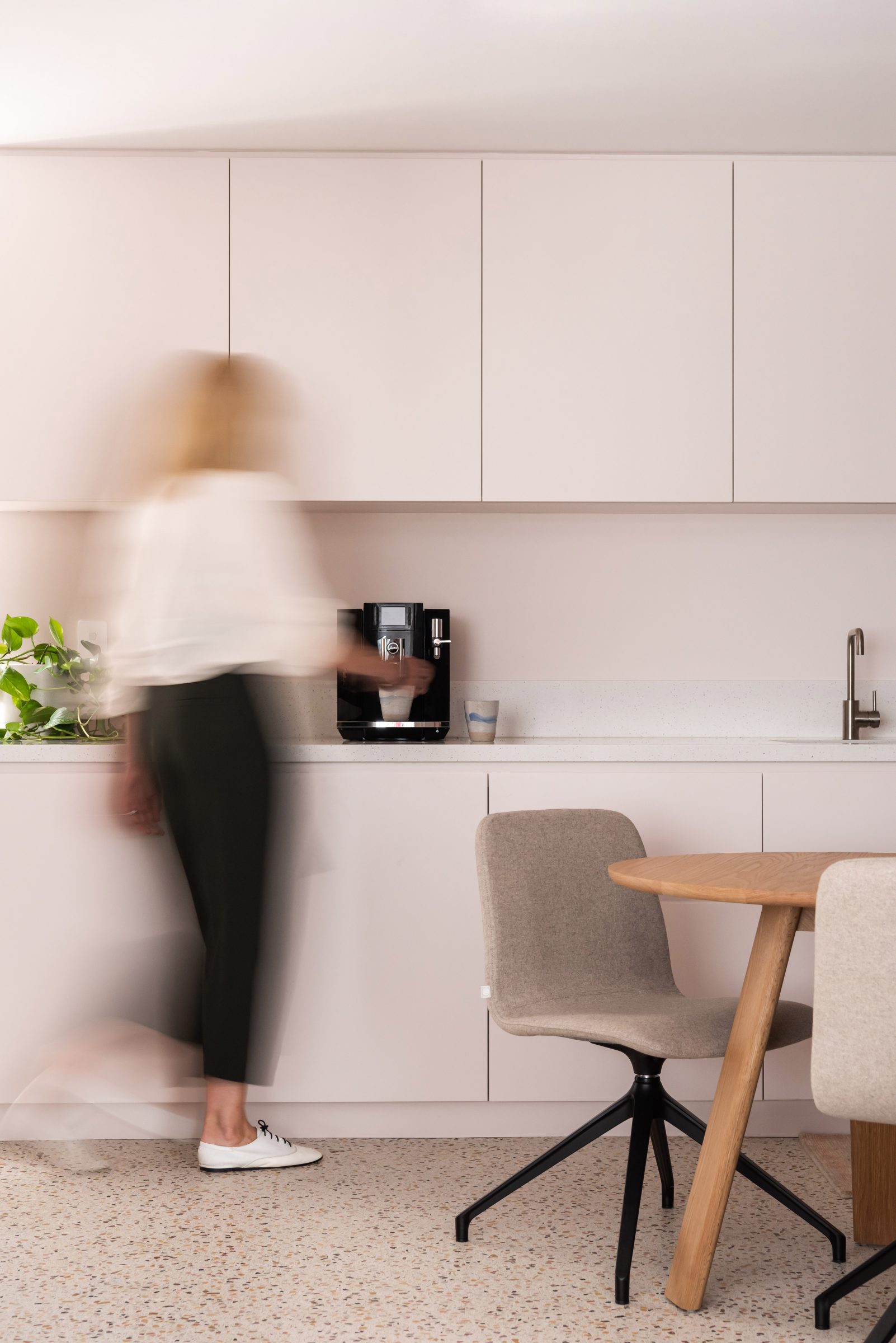 Modern kitchen scene with blurred person and sleek cabinetry from Jardan design collection.