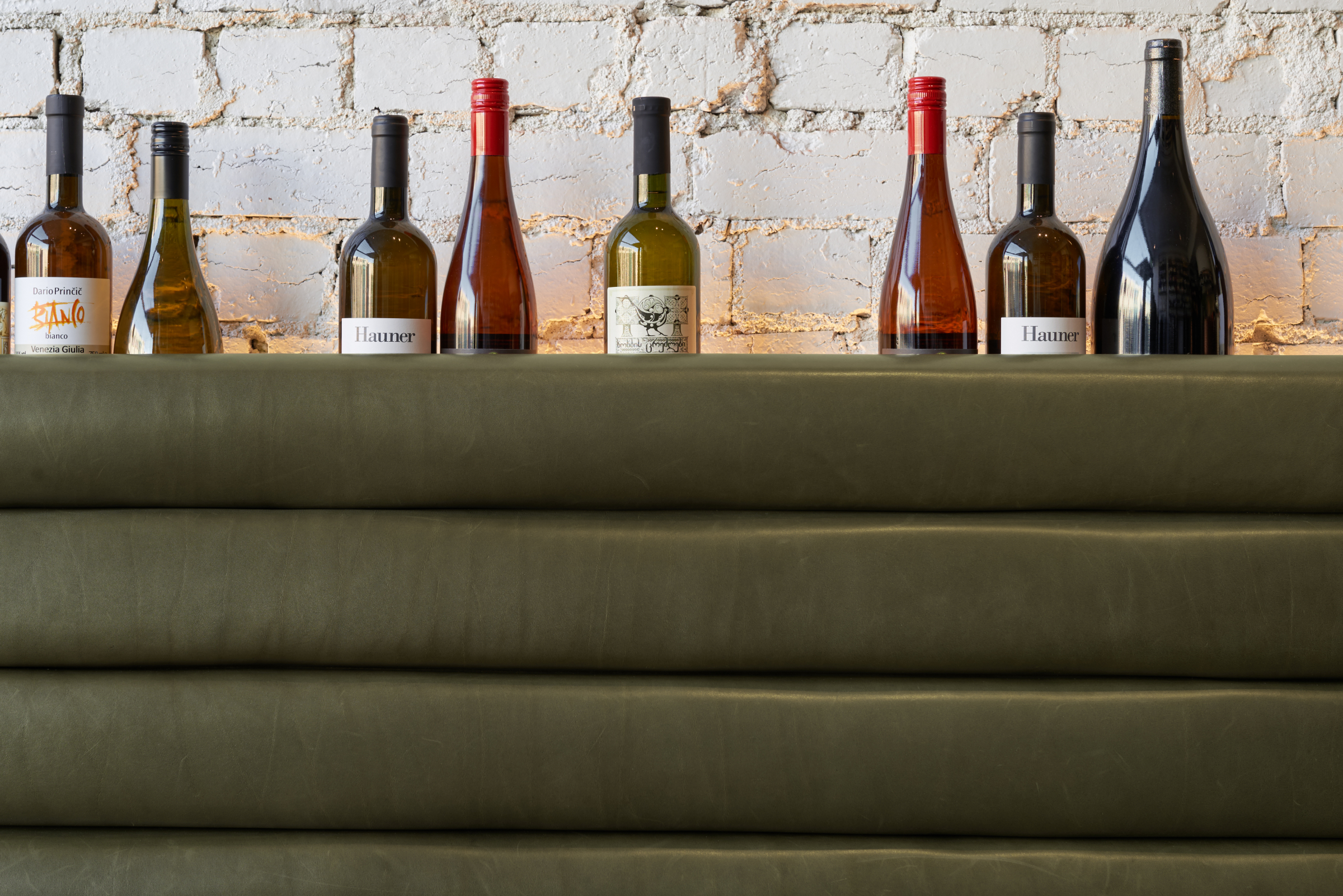 Wine bottles displayed on a shelf against a brick wall part of Marion.