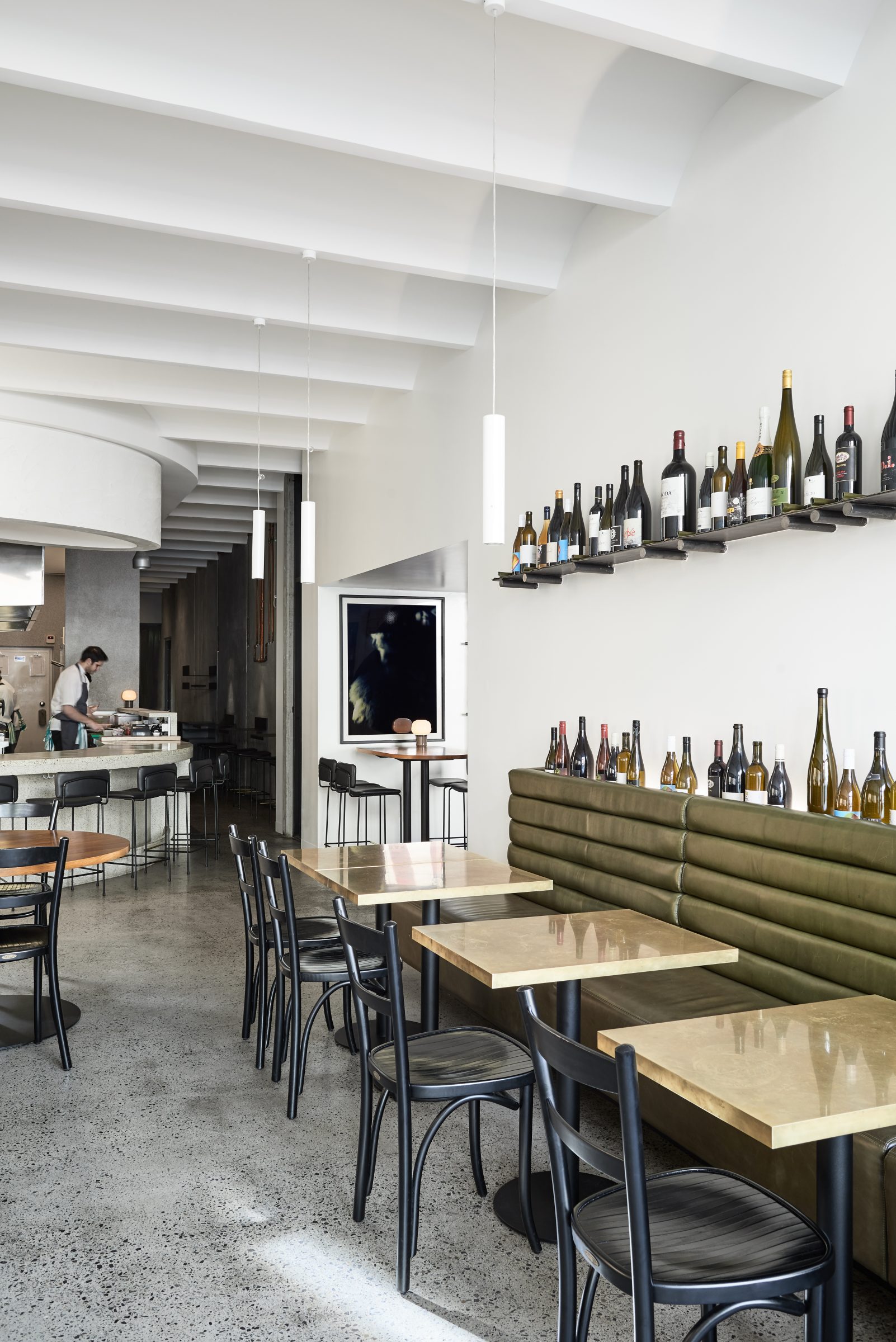 Modern restaurant interior with wine bottles on shelves and tables from the Marion project.