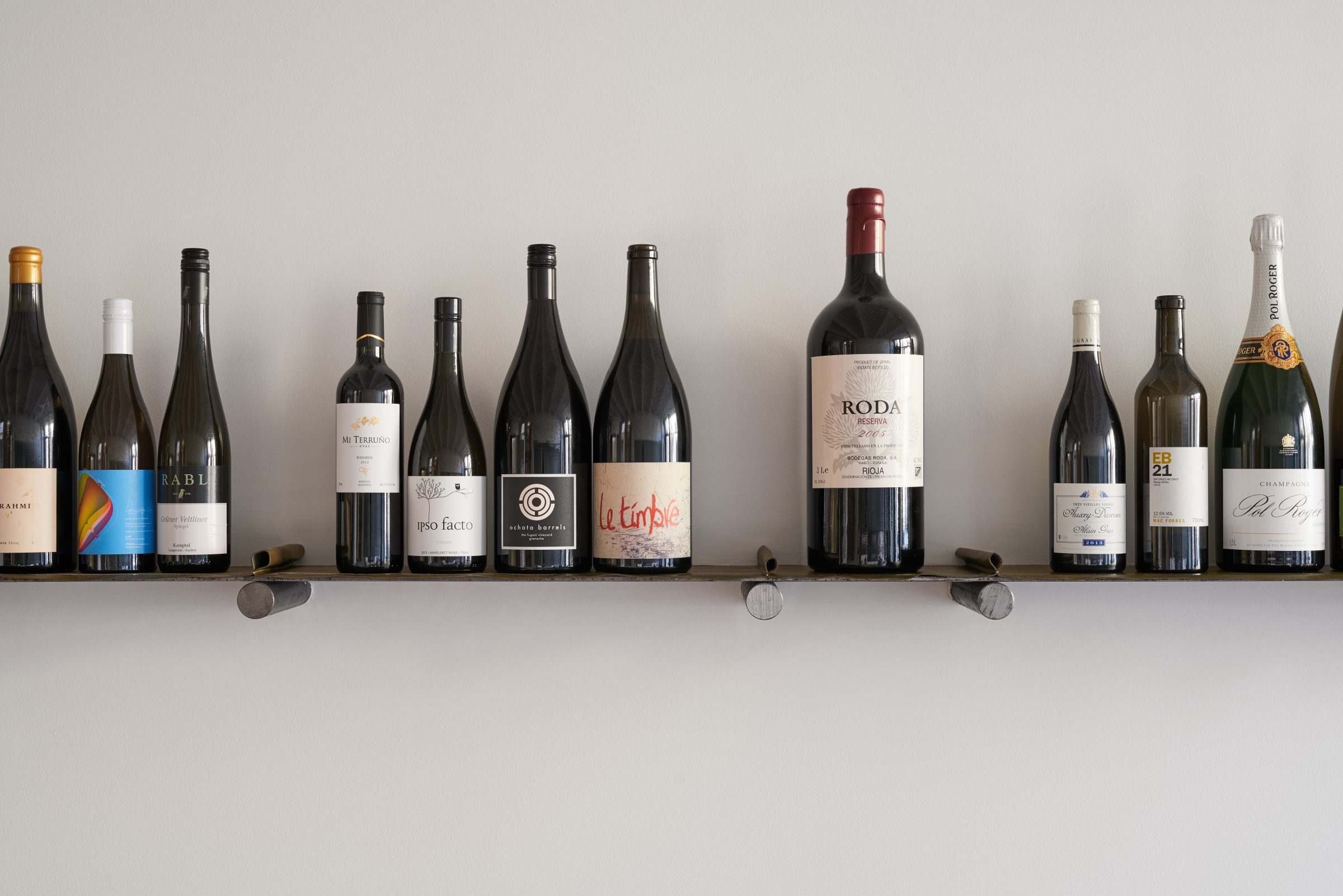 A collection of wine bottles displayed on a minimalist shelf from the Marion project.