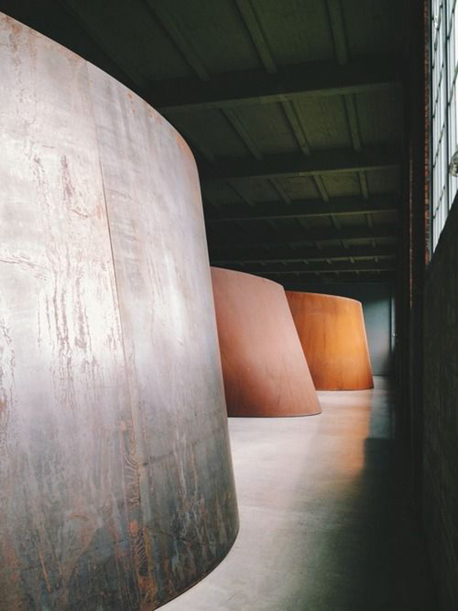 Curved metal sculptures inside a spacious industrial building, part of "Marion".
