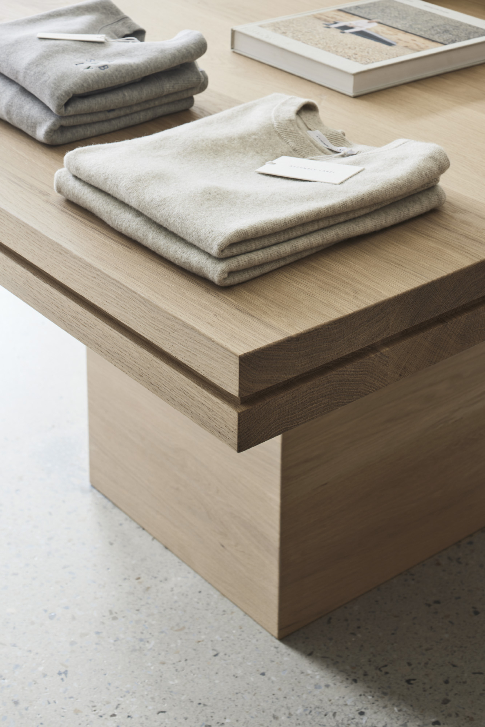 Folded sweaters on a wooden table, part of Assembly Label, Adelaide.