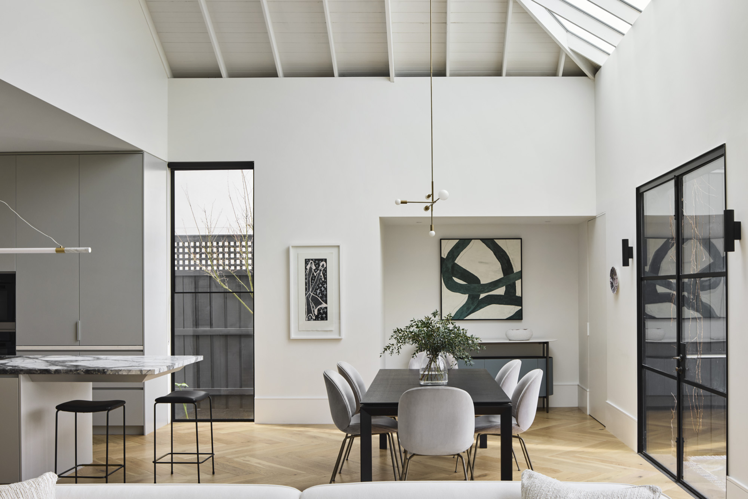 Modern dining area and kitchen in "Day House" with minimalist decor and natural lighting.