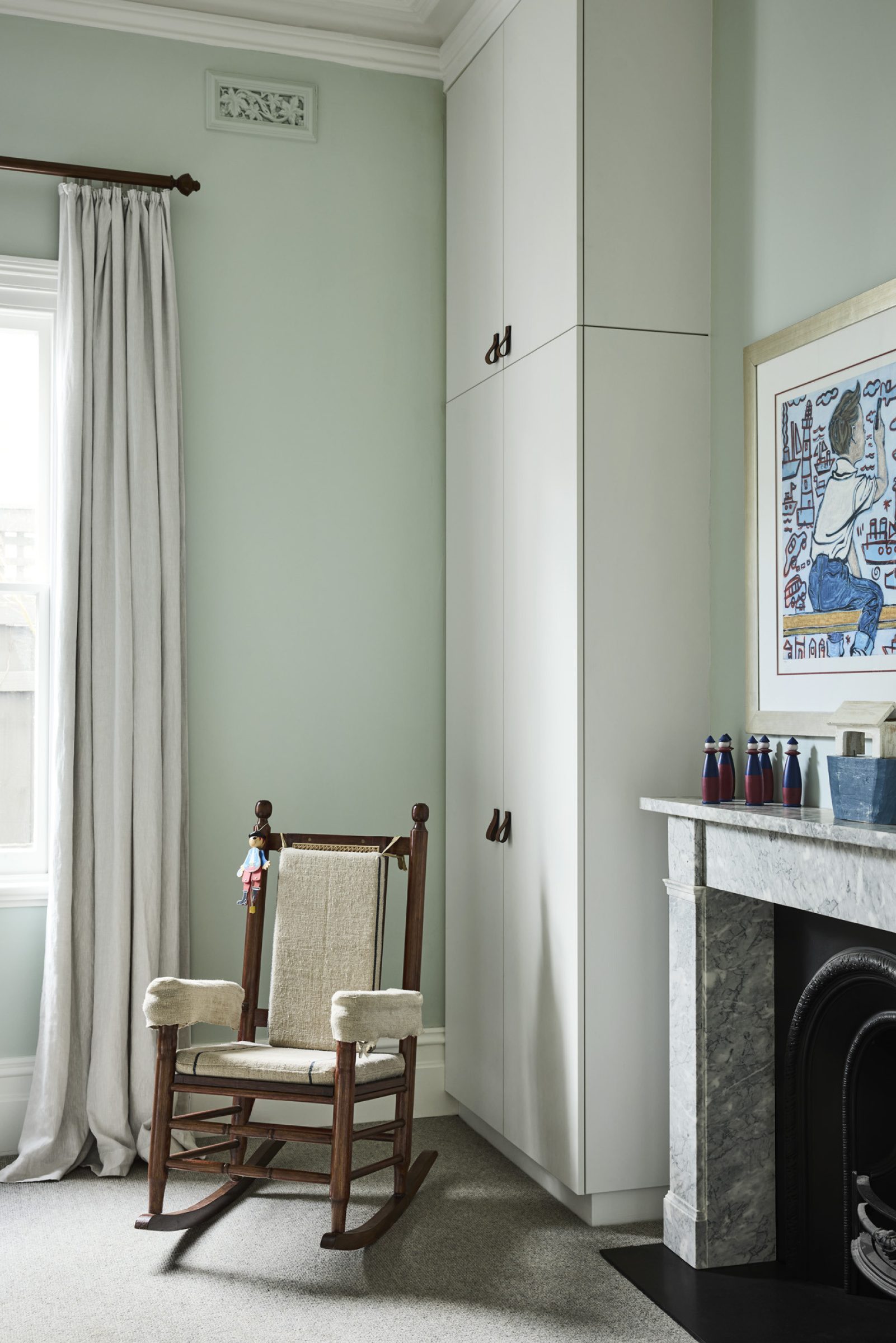 Cozy "Day House" interior with a wooden rocking chair beside a marble fireplace.