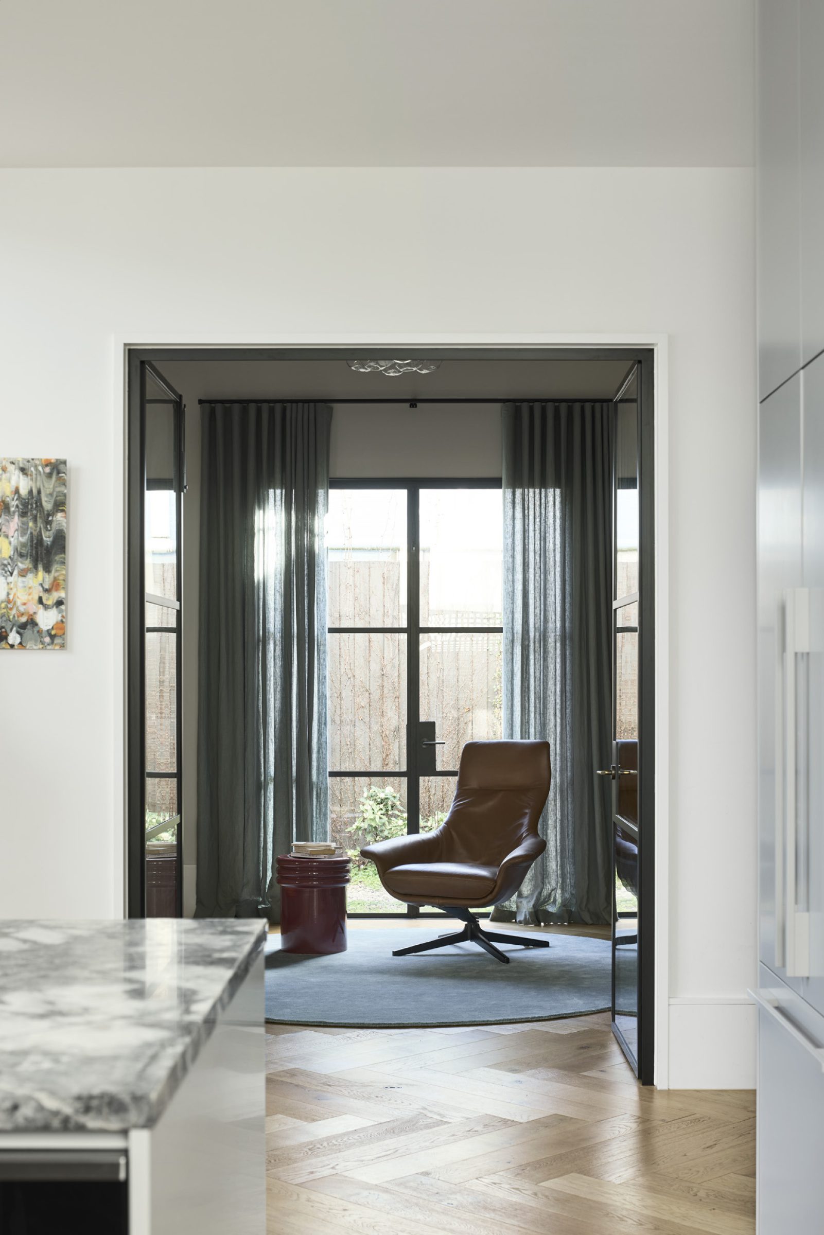 Modern living area with leather chair and large windows in Day House.