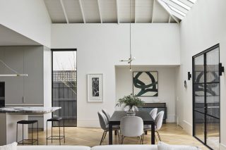 Modern dining area and kitchen in "Day House" with minimalist decor and natural lighting.