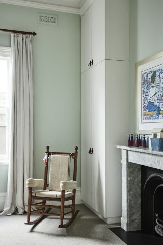 Cozy "Day House" interior with a wooden rocking chair beside a marble fireplace.