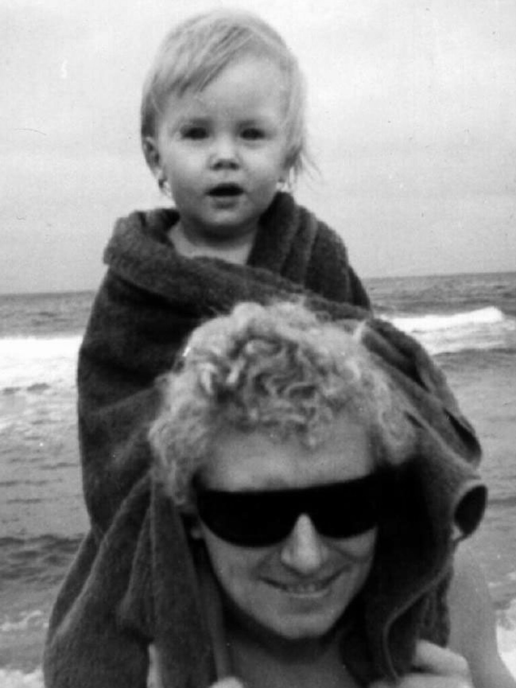 Child sitting on an adult's shoulders at the beach in Jardan Sydney.