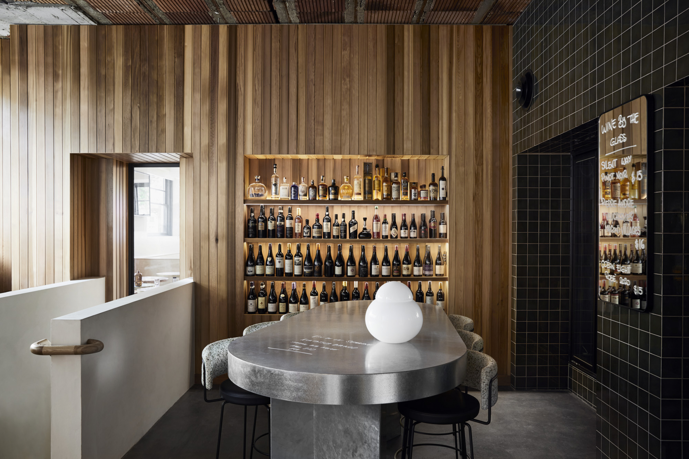 Modern wine bar interior featuring a central table and Little Prince Wine bottle display.