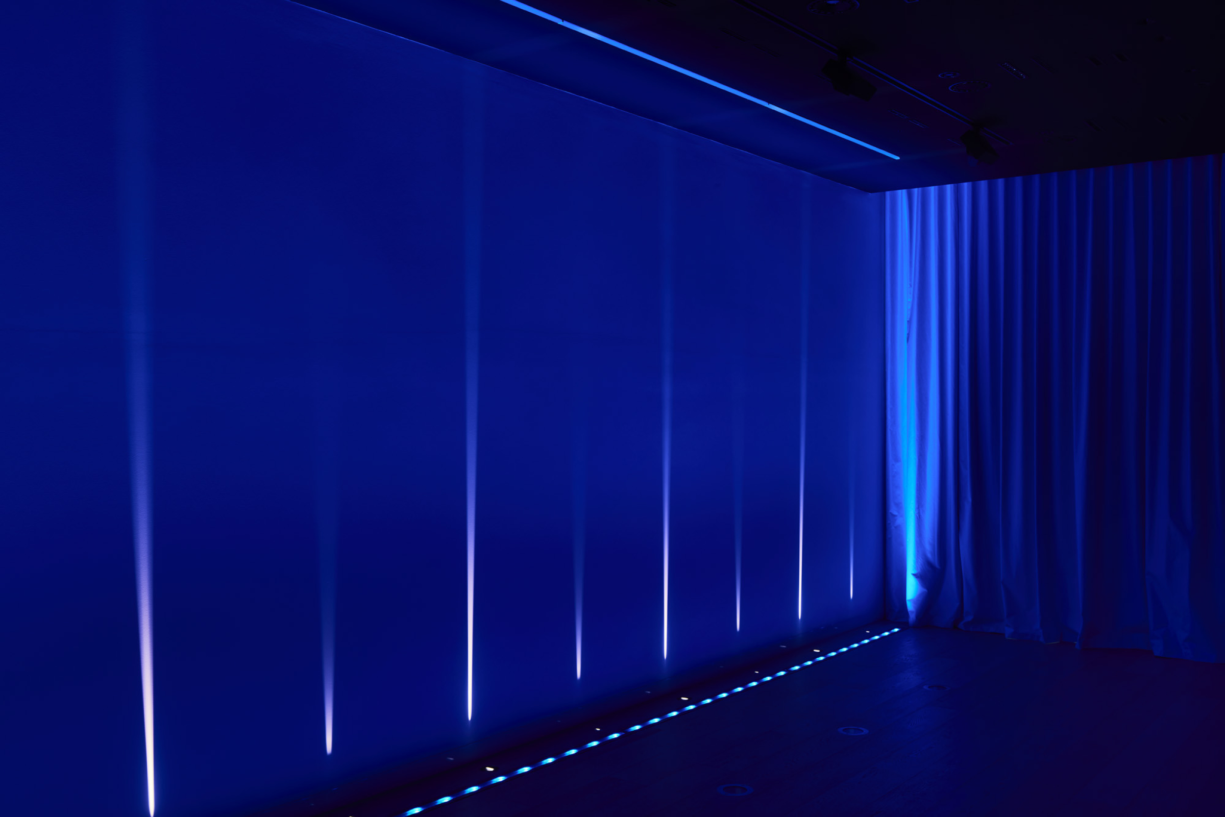 Blue-lit room with vertical light beams and curtains, from Lux-Fx.