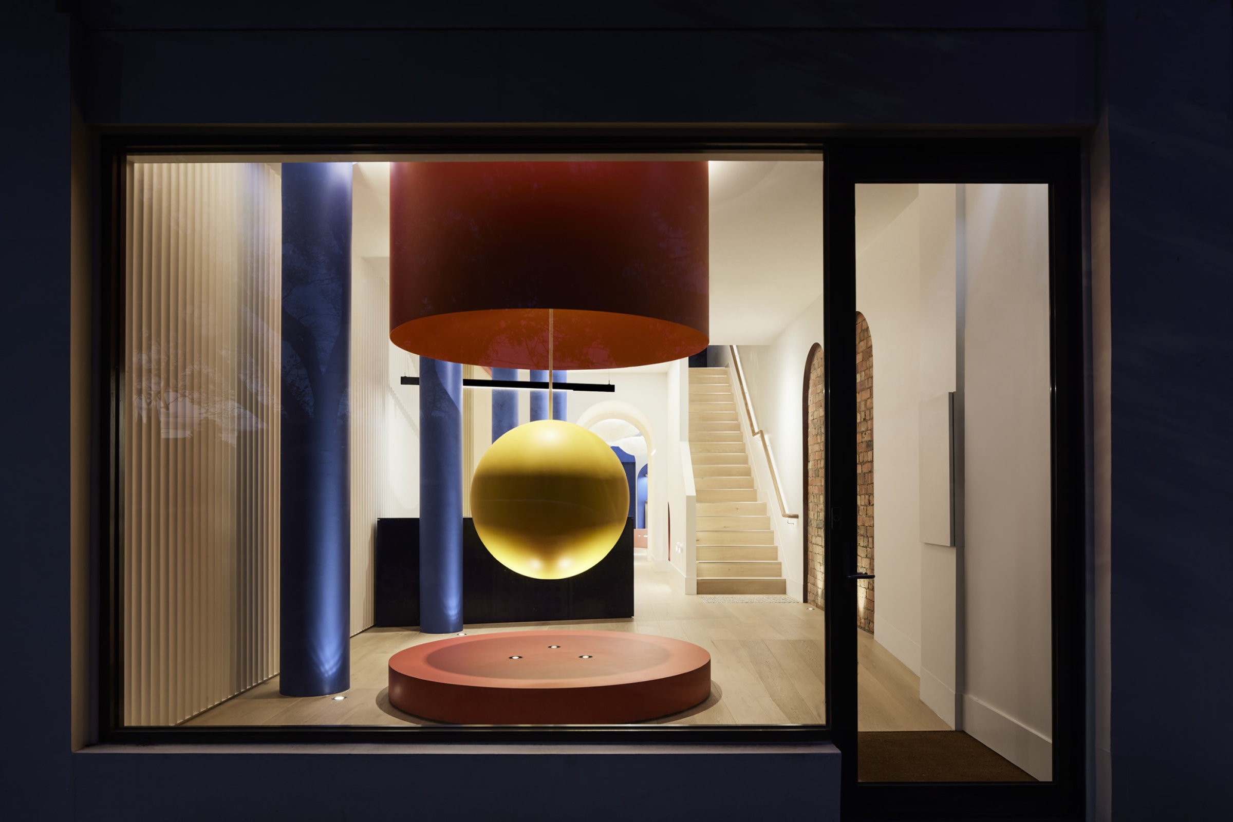 Modern interior with a glowing yellow sphere and staircase, part of Lux-Fx.