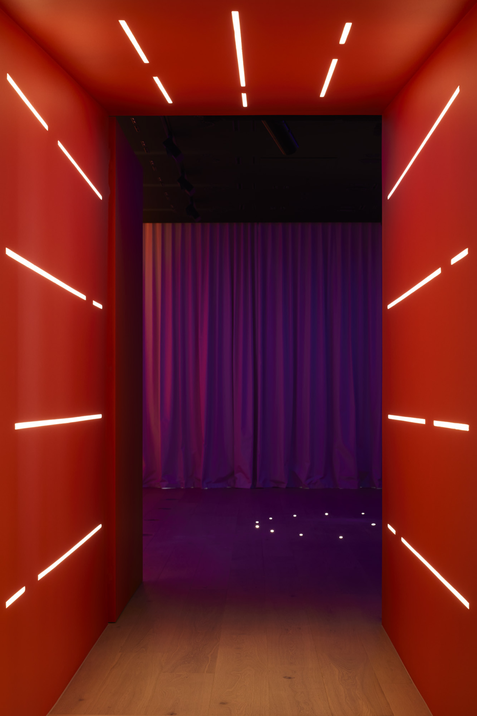 Illuminated red corridor with linear lights, part of Lux-Fx installation.