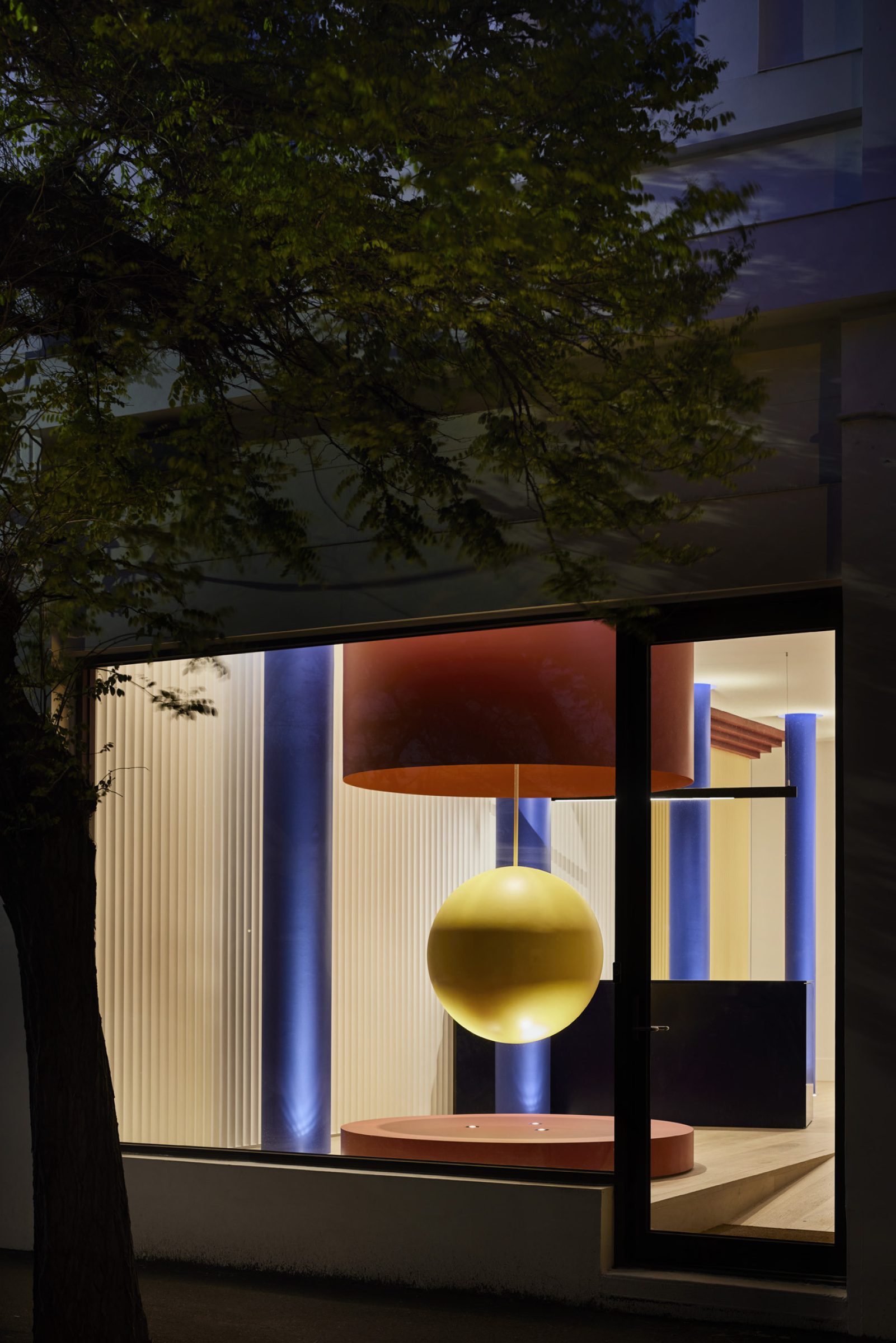 Lux-Fx: Illuminated modern installation with geometric shapes viewed through a large window at night.