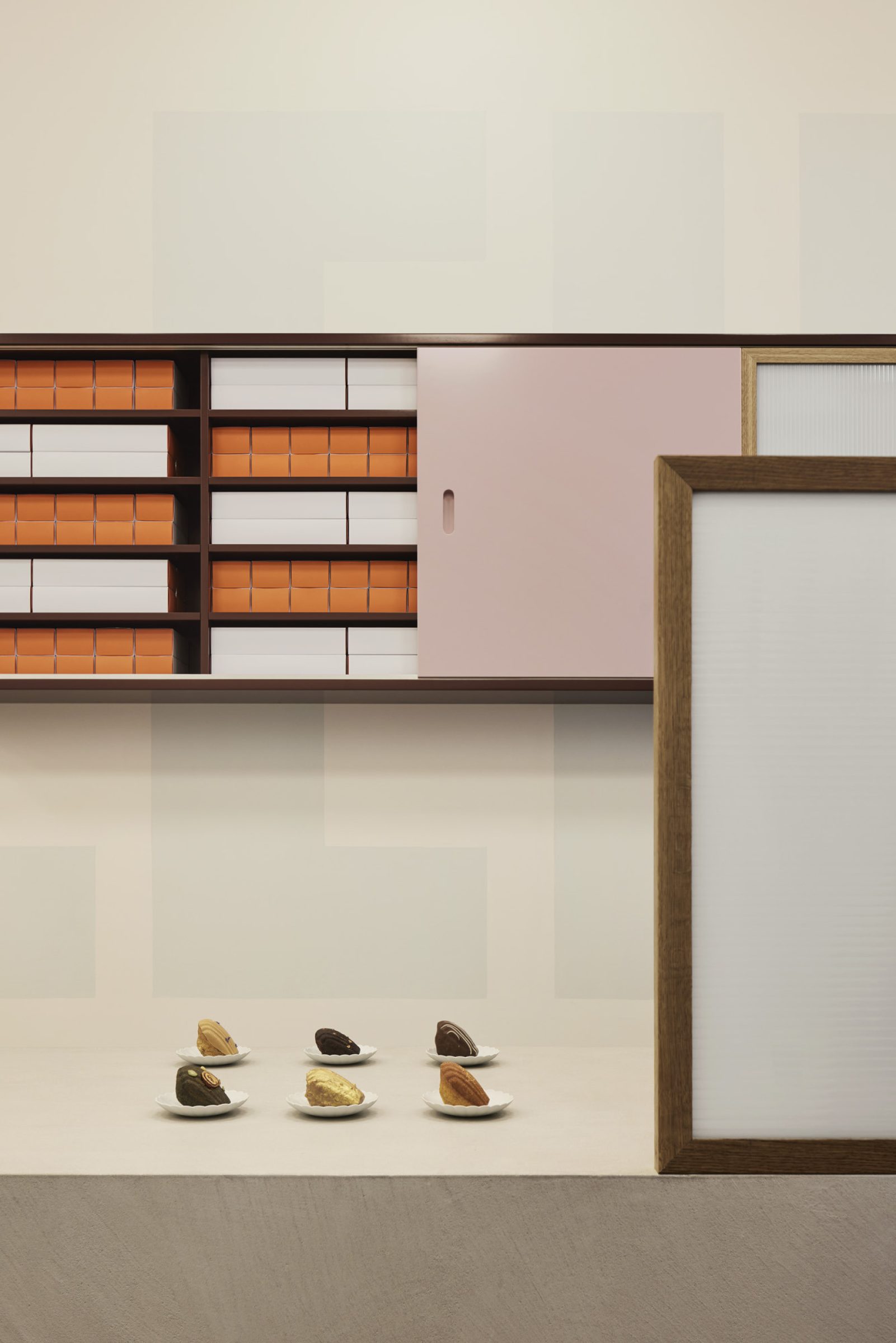 Madeleine de Proust features elegant pastries displayed on a minimalist countertop with organized shelves.