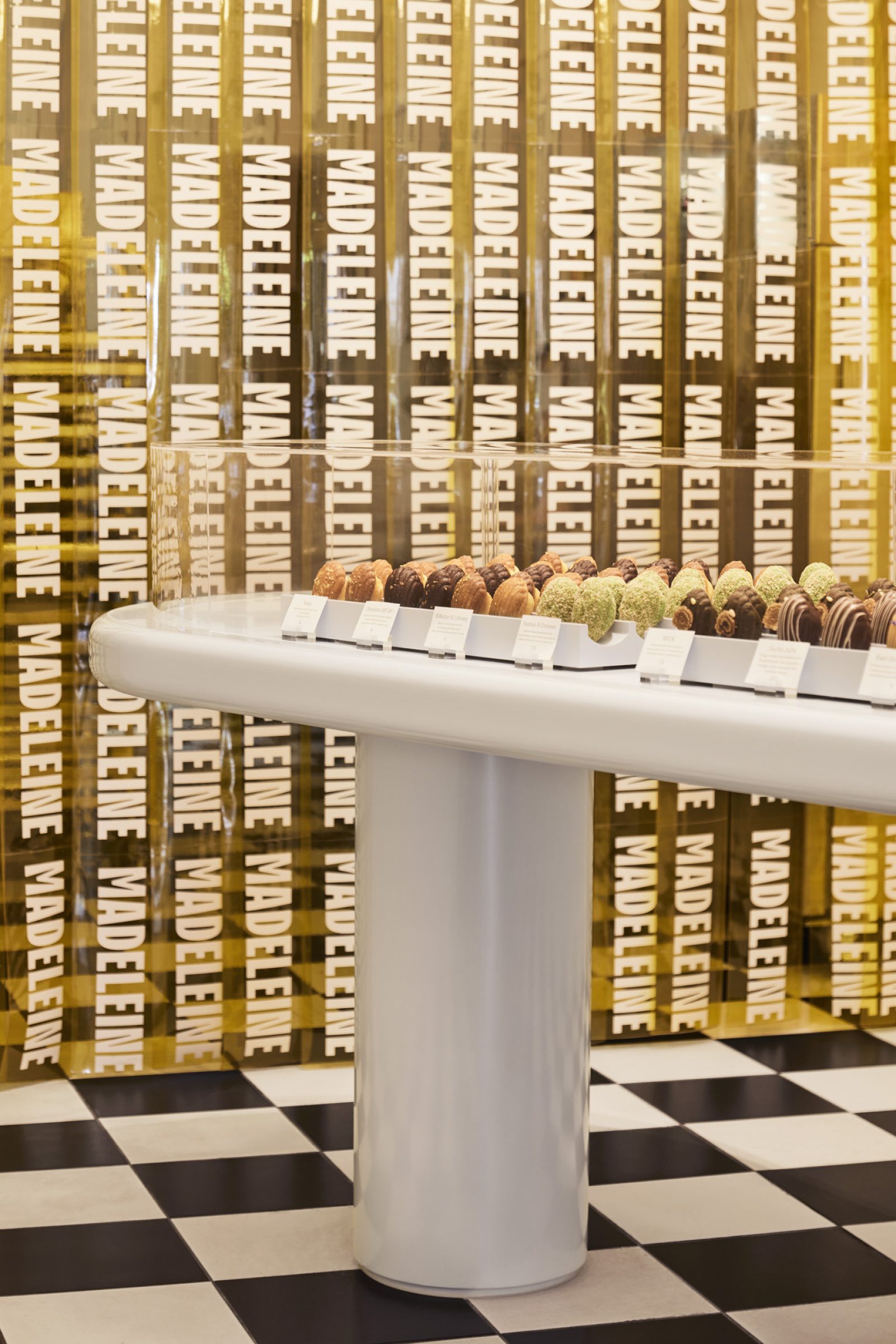Display of madeleines with "Madeleine de Proust" branding in a checkered floor setting.