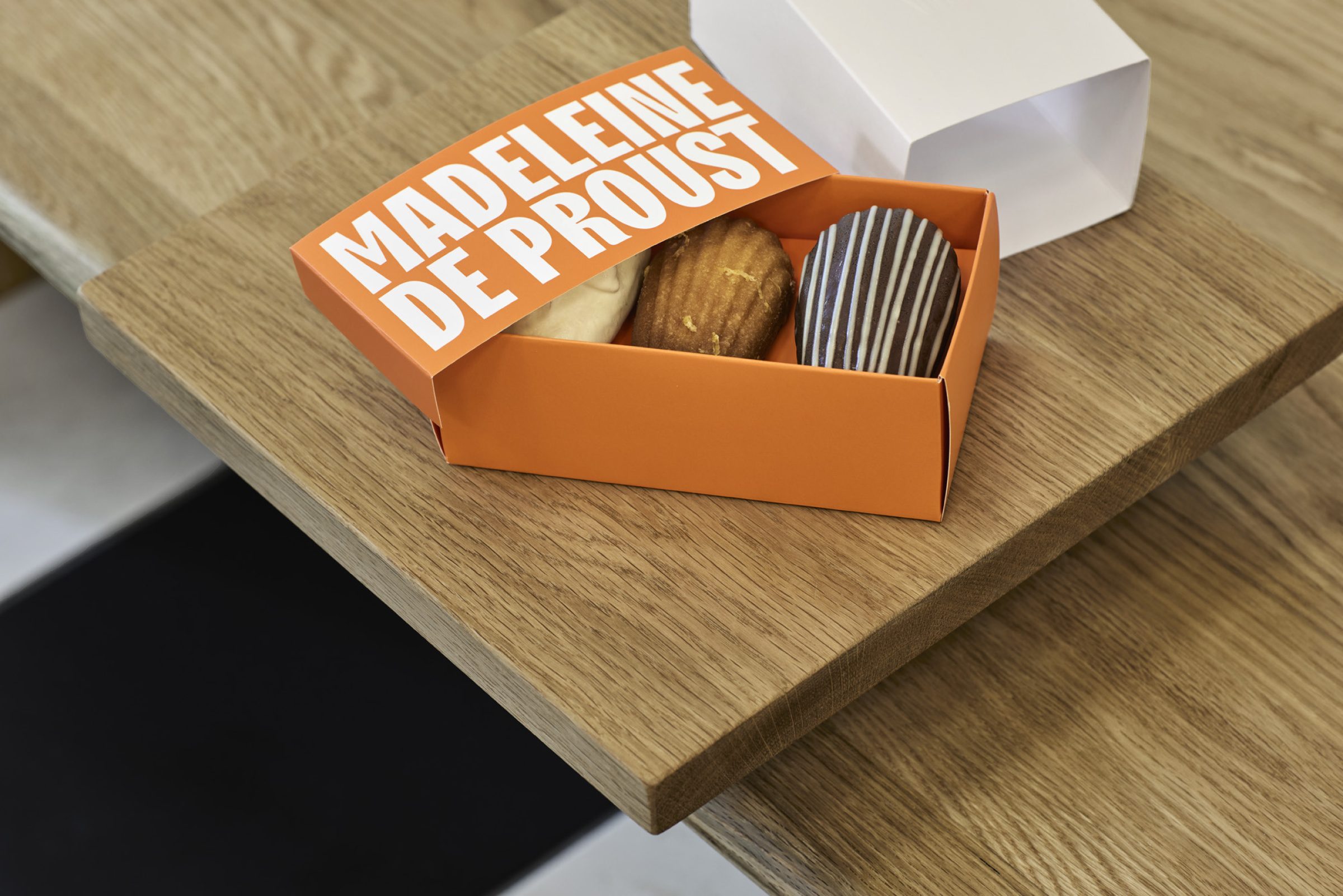 Box of Madeleine pastries labeled "Madeleine de Proust" on a wooden table.