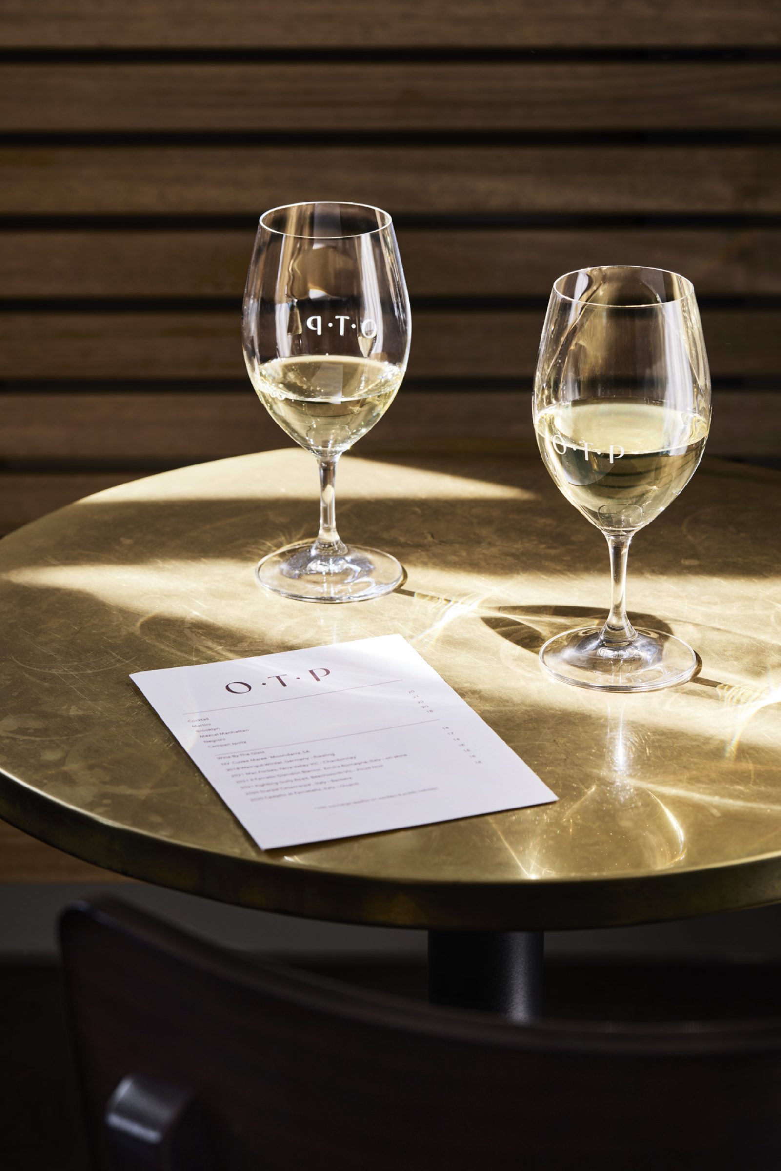 Two wine glasses and a menu on a table, part of "One Trick Pony".