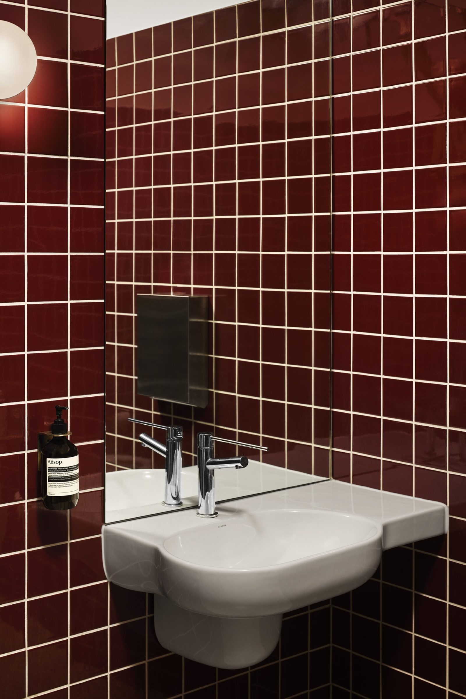 Red tiled bathroom with a wall-mounted sink and Aesop soap, from One Trick Pony.